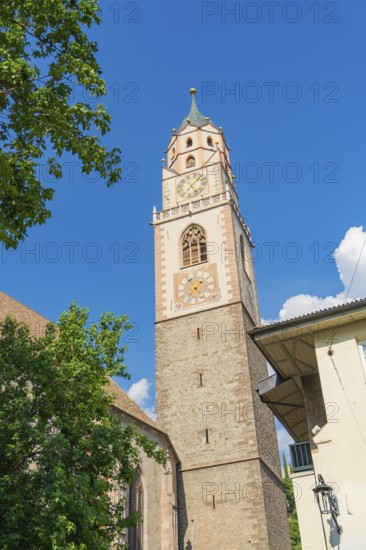 High church tower with clock in front of a blue sky, Merano, South Tyrol, Italy