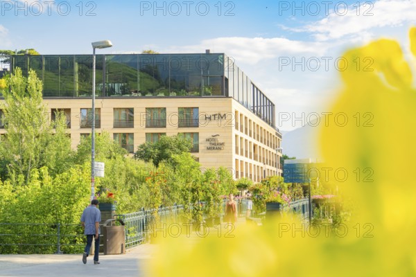Modern hotel view in summer with plants, bright architecture and people walking, Merano, South Tyrol, Italy
