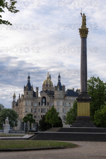 Schwerin Castle rises behind the Victory Column with golden statue, Schwerin, Mecklenburg-Vorpommern, Germany
