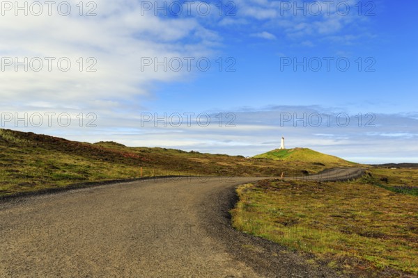 Winding tarmac road leads through barren volcanic landscape, Reykjanesviti lighthouse on the horizon, Reykjanes peninsula, near Reykjavik, Iceland