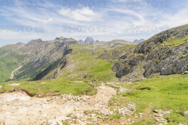 Expansive view of mountain landscape with green grass and blue sky full of clouds, Schlehrn hike, Alpe di Siusi, Dolomites, South Tyrol, Italy