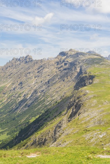 Steep mountain range with green slopes and striking sky in the background, Schlehrn hike, Alpe di Siusi, Dolomites, South Tyrol, Italy