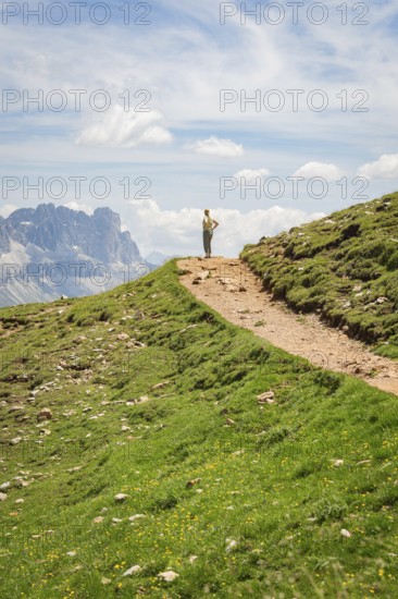 Hikers on a path in a mountainous landscape under a blue sky, Schlehrn hike, Alpe di Siusi, Dolomites, South Tyrol, Italy