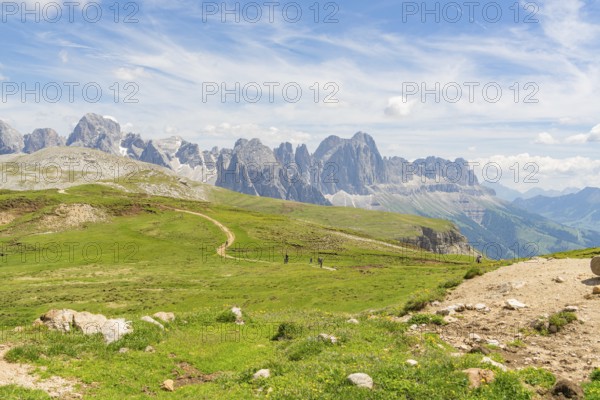 Panorama of a mountain path in the middle of a vast mountain landscape under a blue sky, Schlehrn hike, Alpe di Siusi, Dolomites, South Tyrol, Italy