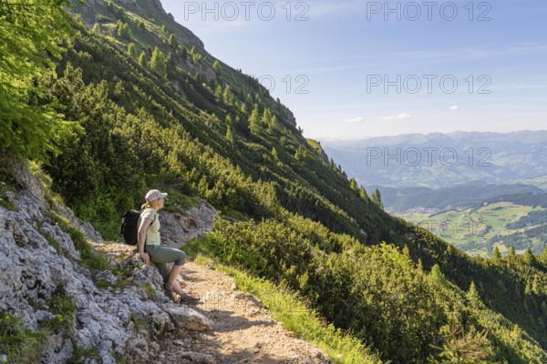 Hiker sitting on a mountain path with a view of the valley, hike to the Schlehrn, Alpe di Siusi, Dolomites, South Tyrol, Italy