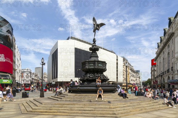 People sitting around Eros statue, Piccadilly Circus, central London, England, UK - Shaftesbury Memorial Fountain