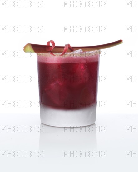 Cocktail in a tumbler on ice with rhubarb stalk as garnish against a white background, studio shot
