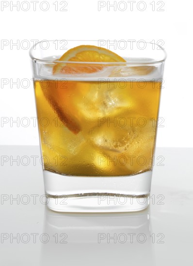 Cocktail in a tumbler on ice with half a slice of orange as garnish against a white background, studio shot
