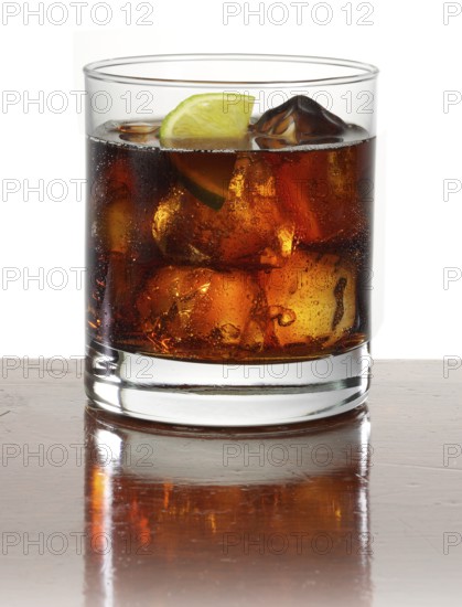 Cocktail in a tumbler on ice with half a slice of lime as garnish against a white background, studio shot
