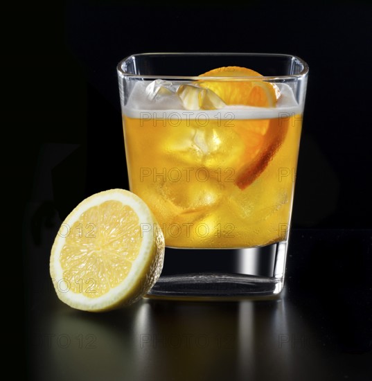 Cocktail in a tumbler on ice with half a slice of orange and half a lemon as garnish against a black background, studio shot
