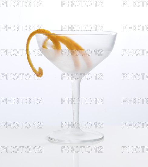 Frosted empty cocktail glass with orange zest as garnish against a white background, studio shot