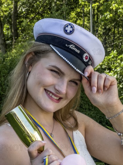 Happy blonde student on graduation day, holding her cap and smiling at the camera, in Ystad, SkÃ¥ne County, Sweden, Scandinavia