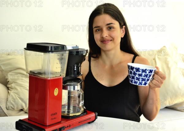 Young beautiful Southern European woman, brunette, 30 years old, demonstrating a coffee machine in Ystad, SkÃ¥ne County, Sweden, Scandinavia