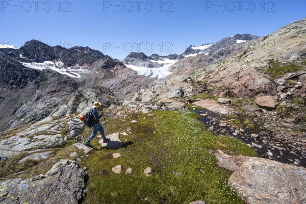 Mountaineer walking over stones, rocky mountain landscape, behind Königshofspitz, Schwarzwandspitz and glacier Ãœbeltalferner, descent from the summit Roter Grat, Stubai Alps, South Tyrol, Italy