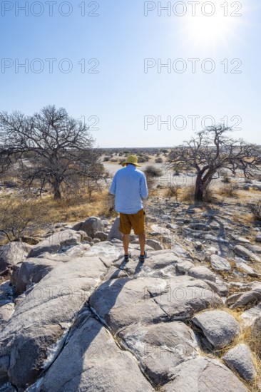 Tourist on a hill with baobabs, African baobab or monkey bread tree (Adansonia digitata), view over Kubu Island (Lekubu), Sowa Pan, Makgadikgadi salt pans, Botswana