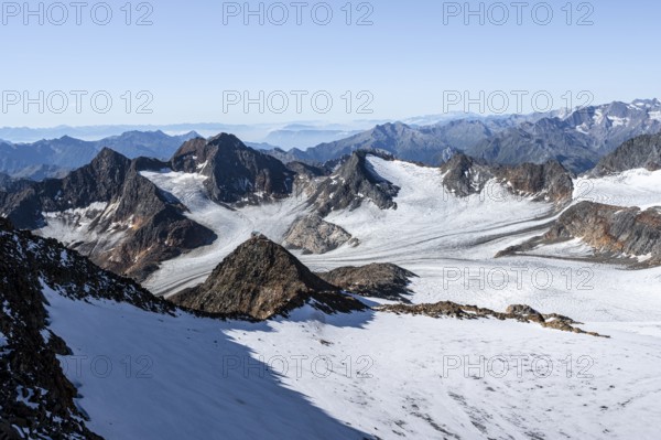 Narrow rocky ridge at the Wilder Freiger summit, picturesque high mountain landscape with snow, view of Ãœbeltalferner glacier and rocky mountain peaks Königshofspitz and Sonklarspitze, Stubai Alps, South Tyrol, Italy