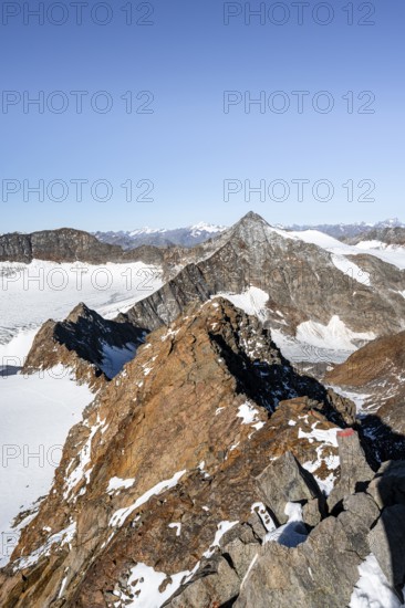 Narrow rocky ridge on the Wilder Freiger summit, picturesque high mountain landscape with snow, view of Ãœbeltalferner glacier and rocky Wilder Pfaff mountain summit, Stubai Alps, South Tyrol, Italy