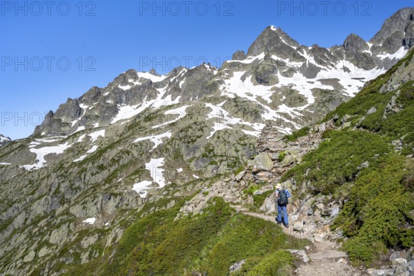 Mountaineer on hiking trail, summit of the Aiguilles rouges with snow remains, Chamonix, Haute-Savoie, France