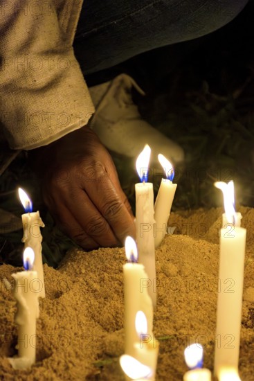 Hand placing a candle as an offering during prayers at a religious festival, Minas Gerais, Brazil