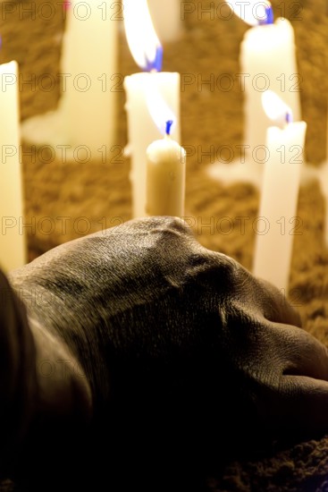 Hand placing a candle as an offering during prayers at a religious festival