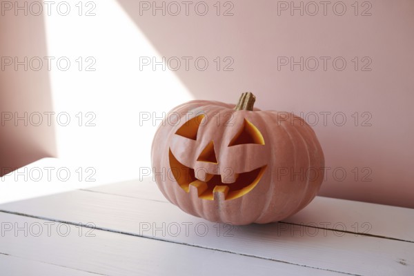 Pink pumpkin resting on wooden surface with shadow and light. Minimalist autumn composition symbolizing nontraditional seasonal decor and modern Halloween aesthetic. Generative ai, AI generated