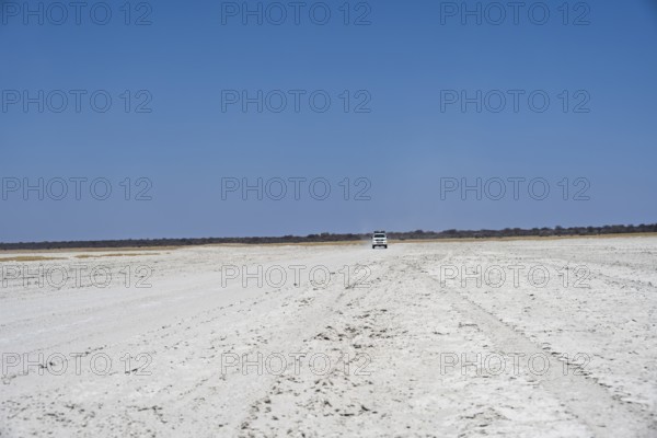Off-road vehicle driving on a wide empty salt pan, Makgadikgadi Salt Pans, Botswana