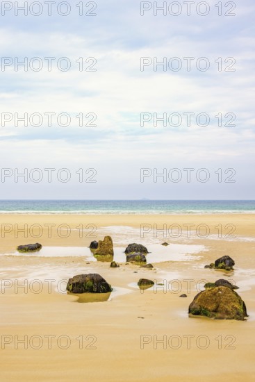 Rocks on a empty sand beach with a sea view towards the horizon in the summer, Crozon Peninsula, Bretagne, France