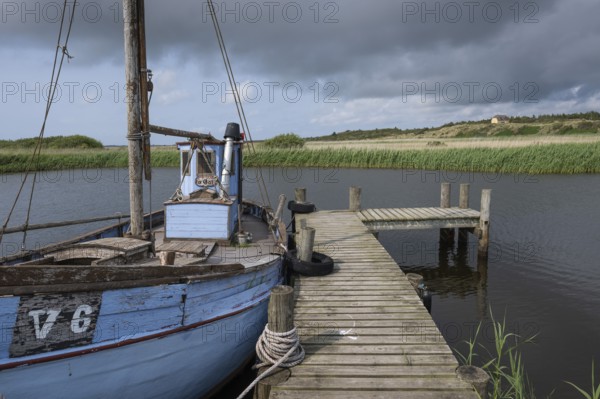 Old blue fishing boat moored at wooden jetty, RingkÃ¸bing Fjord, old fishing village Nymindegab, Jutland, Denmark