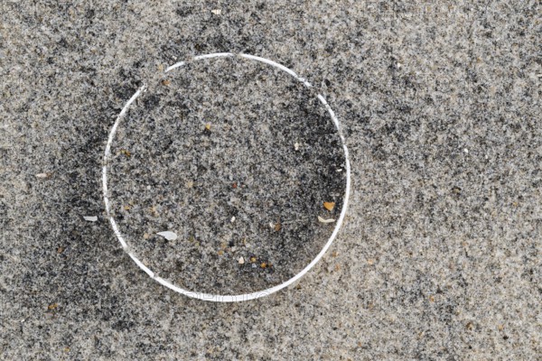 Remains of a plastic bottle in the sand on the beach, symbolising environmental pollution and human waste, RingkÃ¸bing Fjord, Jutland, Denmark