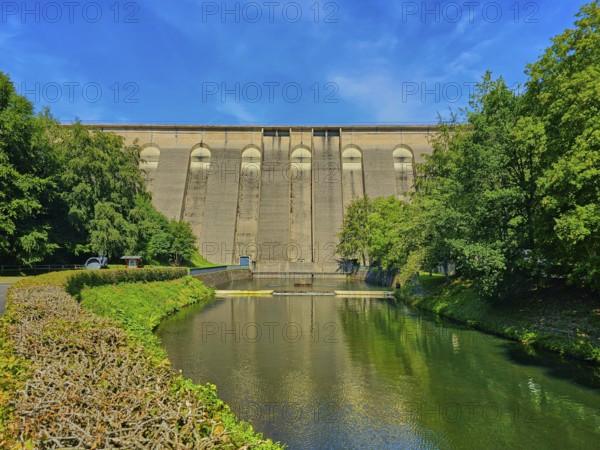 Large dam wall in the foreground, flanked by river and lush trees under a clear blue sky, Oleftalsperre, Hellenthal, Eifel, North Rhine-Westphalia, Germany