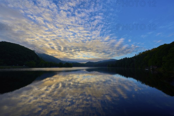 Peaceful morning atmosphere with dramatic sky reflected on the still lake, surrounded by green mountains, summer, Rursee, Obersee, Rurberg, Simmerath, Eifel National Park, Eifel, North Rhine-Westphalia, Germany