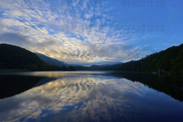 Impressive morning view with reflecting sky on a calm lake, framed by gentle mountains, summer, Rursee, Obersee, Rurberg, Simmerath, Eifel National Park, Eifel, North Rhine-Westphalia, Germany