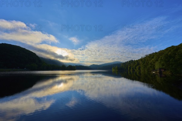 A tranquil lake reflecting dramatic sky and clouds offers a calming view with sweeping mountains, summer, Rursee, Obersee, Rurberg, Simmerath, Eifel National Park, Eifel, North Rhine-Westphalia, Germany
