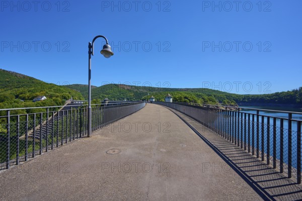 Asphalted bridge with railing over a water reservoir under a blue sky, summer, Urft dam, Obersee, Urftsee, Schleiden, Eifel National Park, Eifel, North Rhine-Westphalia, Germany