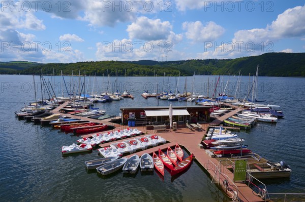 Pedal boats and other boats are moored on a jetty in a large lake and offer leisure activities, summer, Rursee, Rurtalsperre, Heimbach, Simmerath, Eifel National Park, North Rhine-Westphalia, Germany