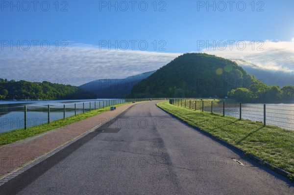 Paulushof barrier dam, dam road along a lake in a mountainous landscape, morning light and clear sky, summer, Rursee, Obersee, Rurberg, Simmerath, Eifel National Park, North Rhine-Westphalia, Germany