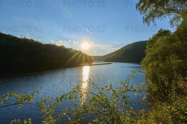 Sunset reflected in the lake, surrounded by forest and hills, summer, Rursee, Obersee, Simmerath, Eifel National Park, North Rhine-Westphalia, Germany