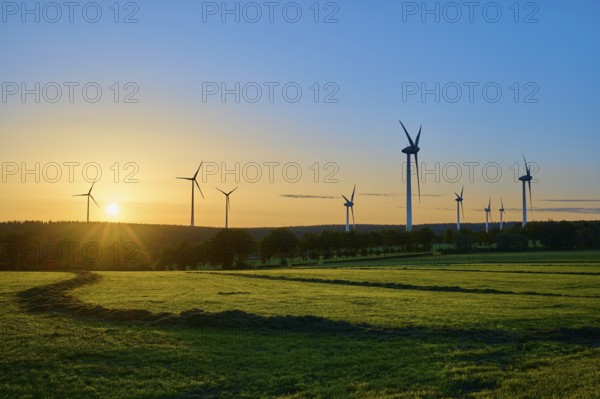 Series of wind turbines at sunrise, play of lights on a green meadow, summer, Rohren, Monschau, Eifel, North Rhine-Westphalia, Germany