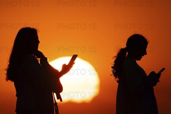 People photographing the sun setting on the horizon with their smartphones from the summit of the GroÃŸer Feldberg in the Taunus, GroÃŸer Feldberg in the Taunus, Schmitten, Hesse, Germany
