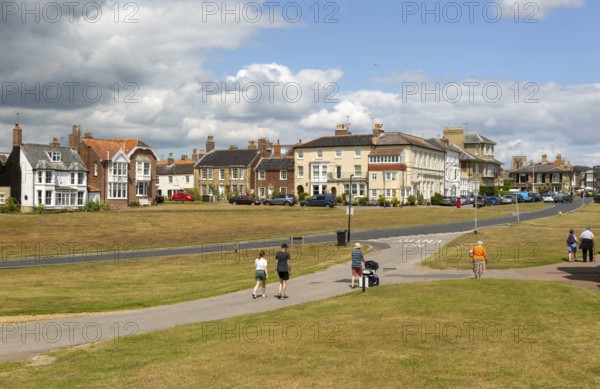People walking on paths on grass area next to Queens Road, Southwold, Suffolk, England, Uk