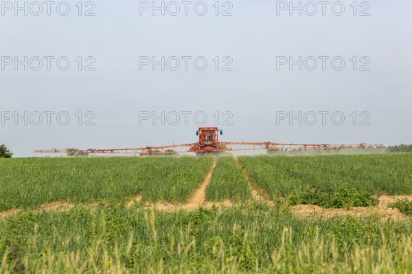 Tractor and crop sprayer spraying arable field, Capel St Andrew, Suffolk, England, UK
