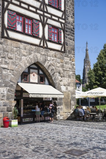 Ice cream parlour and outdoor catering at the Schelztorturm, historic half-timbered building, city gate in Esslingen's old town, on the right the bell tower of the Church of Our Lady, Esslingen am Neckar, district of Esslingen, Baden-WÃ¼rttemberg, Germany