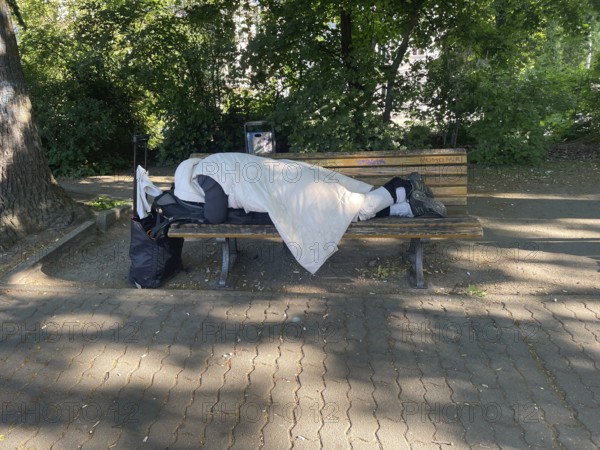 Homeless man sleeping on a park bench in Viktoriapark, District Friedrichshain-Kreuzberg, Social issue, Poverty, Homelessness