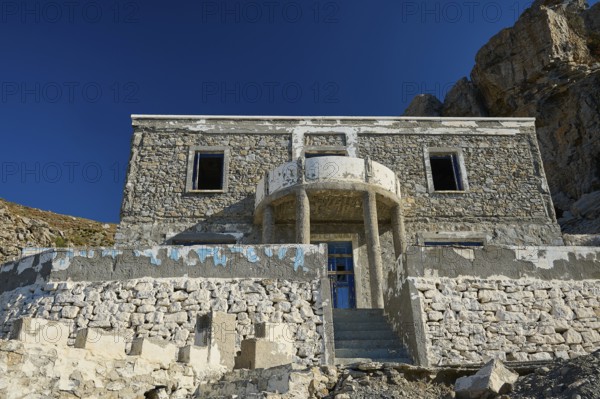 Old stone house against an imposing rocky backdrop, historic and sunlit, Embros Thermal Baths, Kos, Dodecanese, Greek Islands, Greece