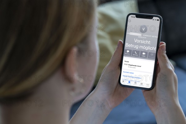 Symbolic image of mobile phone scam, warning of fraudulent calls, here the provider Vodafone, warns the mobile phone user that the caller may have a suspicious number that suggests fraud, spam protection system, the caller's number is stored in a database in which suspicious spam callers are stored, prevention of fraud attempts via mobile phone