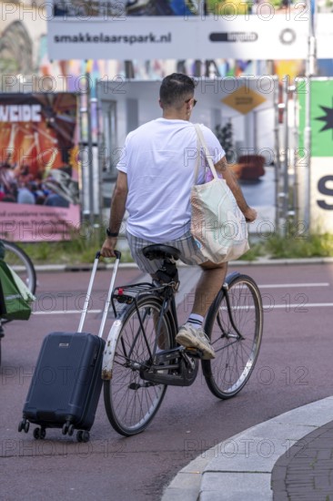 Cycling in the Netherlands, Utrecht, Cyclist pulling a wheeled suitcase behind him