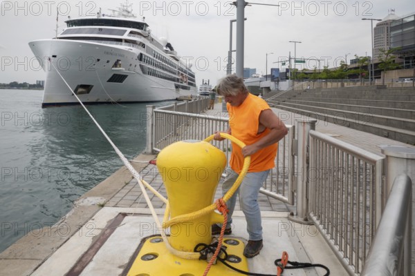 Detroit, Michigan - The Viking Octantis luxury cruise ship in Detroit on a cruise through the Great Lakes. A Port of Detroit worker removes mooring lines as the ship prepares to depart