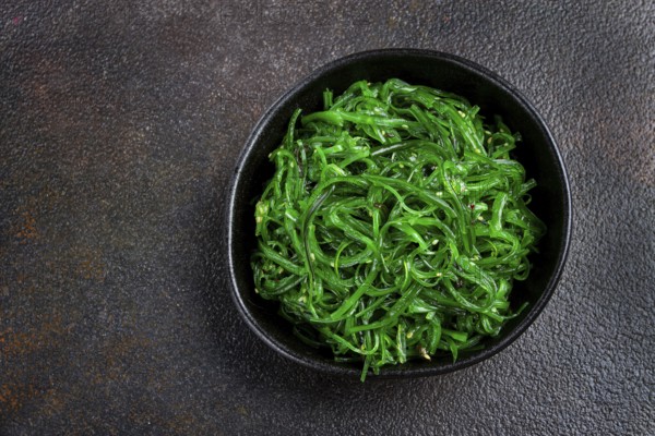 Chuka salad, made from fresh seaweed, with sesame dressing, served in a black bowl, with chopsticks