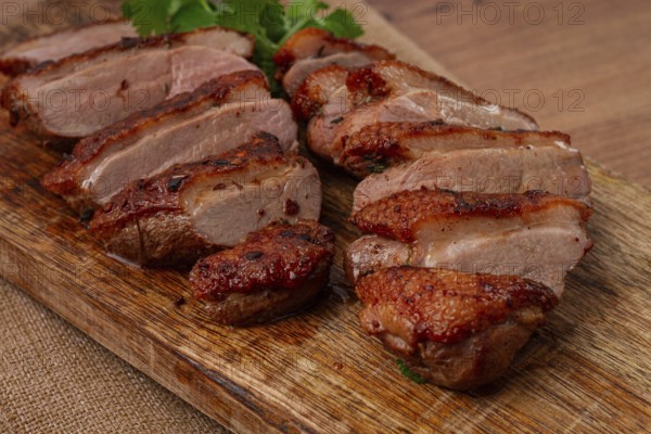 Roast duck breast, sliced, on a wooden chopping board, close-up, no people
