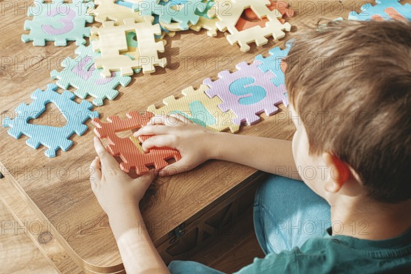 Child assembling colorful puzzle pieces on a wooden table in a bright indoor space during the day